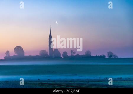 church Mariae Himmelfahrt Kirchreit, late Gothic church at dawn in mist with moon, Germany, Bavaria, Soyen Stock Photo