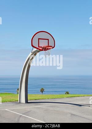 Vertical shot of a basketball hoop near the sea under the beautiful blue sky Stock Photo