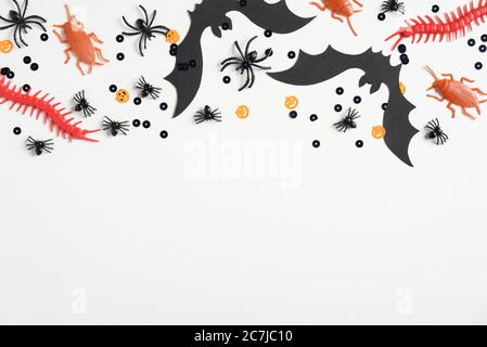 Happy halloween holiday concept. Frame border made of halloween decorations, bats, spiders, insects, confetti on white background. Halloween party gre Stock Photo