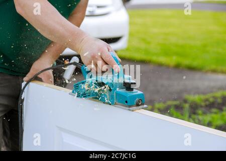 Professional using equipment carpenter maker hand tools on electric planer for processing wooden door Stock Photo
