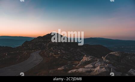 Narrow road leading to a rocky cave under the beautiful sunset sky Stock Photo