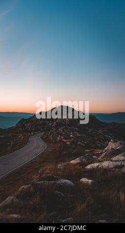 Narrow road leading to a rocky cave under the beautiful sunset sky Stock Photo