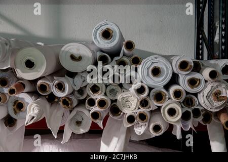 Lot of white textile rolls in a tailors studio Stock Photo
