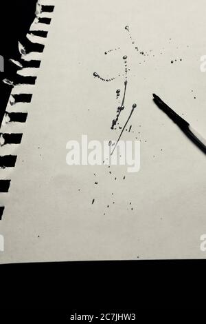 Vertical grey scale shot of a burnt match and some drops of paint on a piece of paper Stock Photo