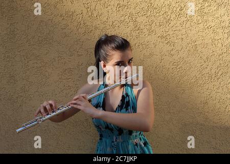 Girl plays the flute in front of a brown background Stock Photo