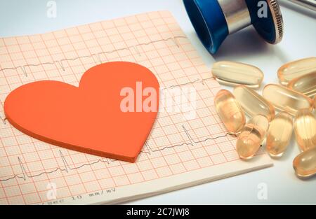 Medical stethoscope, tablets and heart shape on electrocardiogram graph. Medicine and healthy lifestyles. Ekg heart rhythm Stock Photo