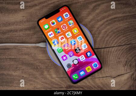 Apple iPhone 11 Pro Max lies on charging pad, wireless charging, Stock Photo