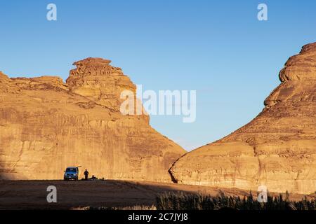 Two men resting between the mountains of Al Ula while the sun is setting, Stock Photo