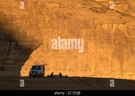 Two men resting between the mountains of Al Ula while the sun is setting. Stock Photo