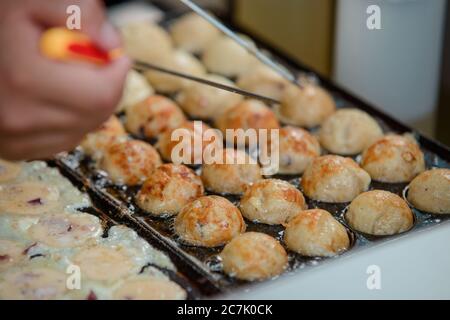 Takoyaki balls being cooked in a pan Stock Photo