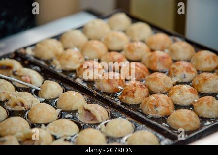 Close up on Takoyaki balls being cooked in a special pan Stock Photo