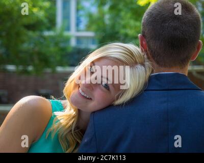 Smiling woman resting her head on the shoulder of a man under the sunlight Stock Photo