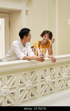 Two young international students happily talking at break in corridor of university Stock Photo