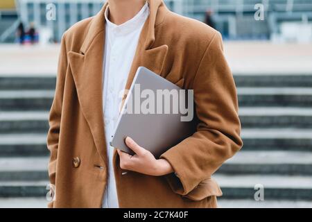 Close up stylish woman in coat with laptop on street Stock Photo