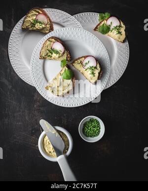 Bread Bread with avocado spread, radishes and fresh chives on three white plates. Stock Photo