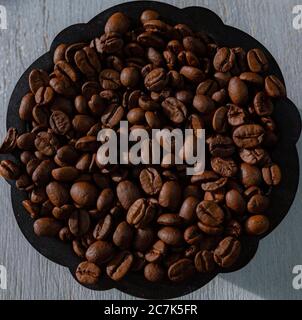 Roasted coffee beans in a bowl on a wooden table Stock Photo