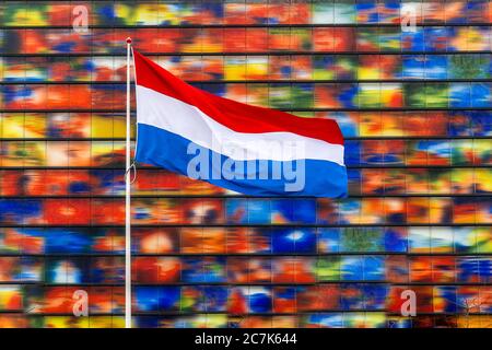 Netherlands flag on the pole with a colorful wall in the background Stock Photo