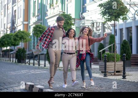 Two girls and a guy with a map bouncing up hugging Stock Photo