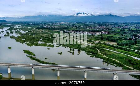 Hanzhong. 18th July, 2020. Aerial photo taken on July 18, 2020 shows a bullet train passing the Hanjiang wetland in Hanzhong City, northwest China's Shaanxi Province. Credit: Tao Ming/Xinhua/Alamy Live News Stock Photo