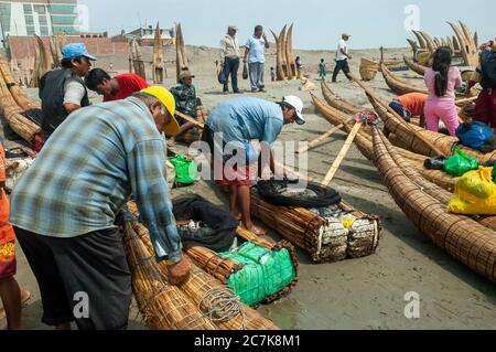 Pimentel beach, Chiclayo, Peru - October 31, 2008: Fishermen on the beach preparing their reed boats. Stock Photo