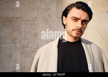 Portrait of young handsome brunette man intently looking in camera outdoor Stock Photo