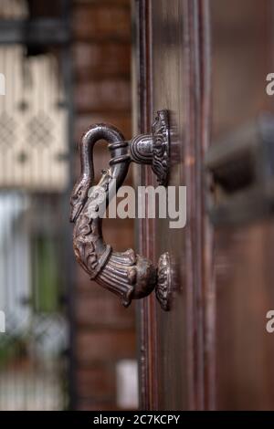 An antique cast iron swan's neck door knocker on a wooden door in Calle Buen Pastor in Córdoba Stock Photo