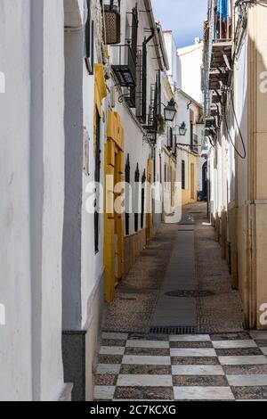 A chequerboard Plaza Ángel de Torres leads to the narrow, winding, Calle Cea in Córdoba's old town Stock Photo