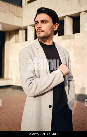 Young handsome man in coat confidently looking away outdoor Stock Photo