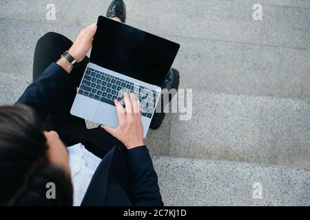 Close up man in classic suit sitting on stairs outdoor working on modern laptop Stock Photo