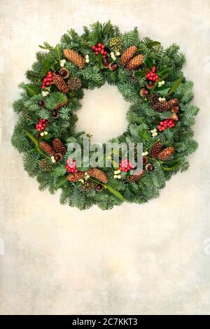 Natural winter greenery wreath for Christmas with spruce fir, holly, pine cones, & mistletoe on old parchment paper. Traditional symbol. Stock Photo