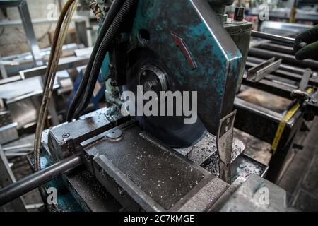 Closeup of an old metal cutting machine in a factory under the lights with a blurry background Stock Photo