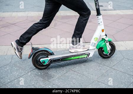 Berlin, Germany - July, 2020: Closeup of a person using a Lime E-scooter or Electric scooter Stock Photo