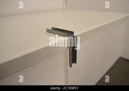 Sets of stapler pins in a twisted position on a white table Stock Photo
