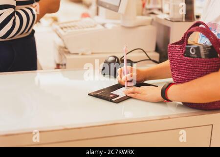 Consumer signature on a sale transaction receipt in shopping mall. Stock Photo