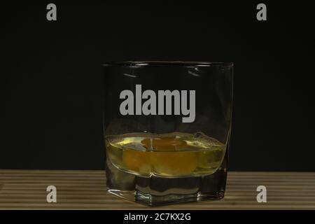 Raw egg in a glass beaker. On a black background Stock Photo