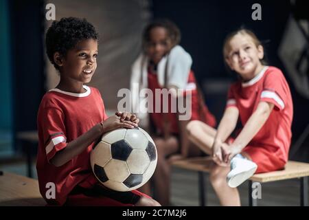 Smiling boy with soccer ball in changing room. Stock Photo