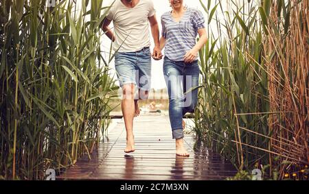 Couple running in the rain.Happy man and woman on the pond on rainy day together. Stock Photo