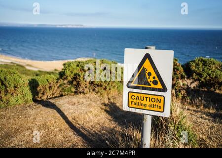 Caution falling cliffs sign on the cliff edge overlooking the sea to the Isle of Wight Stock Photo