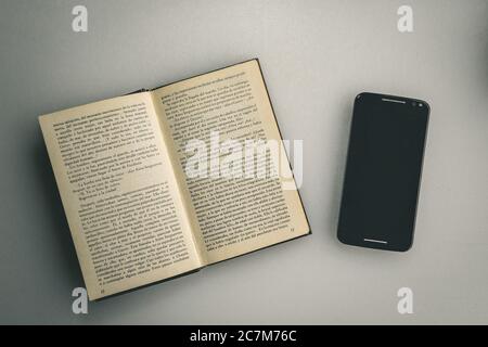 Overhead shot of an open book next to a phone Stock Photo