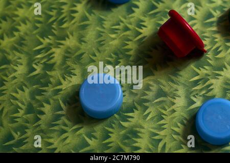 Closeup overhead shot of red and blue plastic bottle caps on a green background Stock Photo