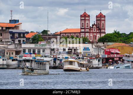 Boats activity on the waterfront of Santarem with a Church beyond, on The River Amazon, Para State, Brazil, Stock Photo