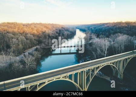 Long shot of a scenic river lined with autumn trees and an arched bridge in the foreground Stock Photo
