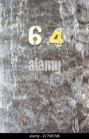 Vertical shot of a wooden wall with metal number 64 on it Stock Photo
