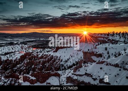 Wide-angle landscape shot of the beautiful Bryce Canyon National Park covered in snow during sunset Stock Photo