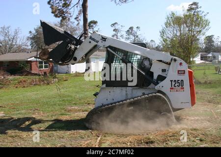 BILOXI, UNITED STATES - Sep 06, 2005: Side-view of loader removing tree trunk felled by Hurricane Katrina. Stock Photo