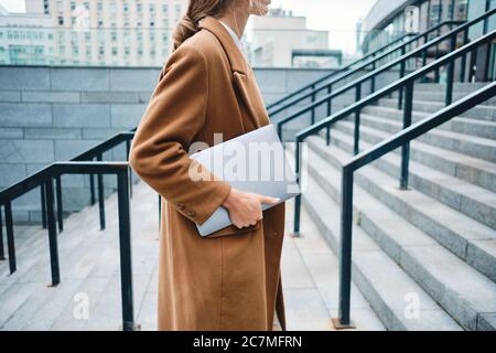 Close up stylish businesswoman in coat with laptop on street Stock Photo