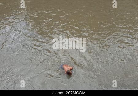 Kathmandu, Nepal. 18th July, 2020. A man gets deep insidet the water to search for things thrown by people during cremation in Bagmati river at premises of Pashupatinath temple in Kathmandu, capital of Nepal on July 18, 2020. Nepali people offer money and gold pieces into water following the religious rituals during the cremation of their beloved ones. Credit: Sunil Sharma/ZUMA Wire/Alamy Live News Stock Photo