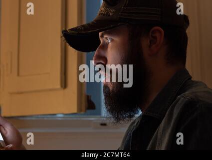 Selective focus of a bearded surprised male looking at his phone Stock Photo