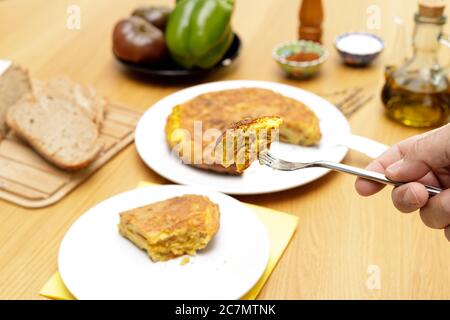 Fork with portion of Spanish omelette close view and table in the background Stock Photo