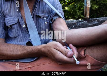 Hands of a drug addict with a syringe full of narcotic, heroin or cocaine to the arm veins. Drugs addiction and obsession. Close up. Stock Photo